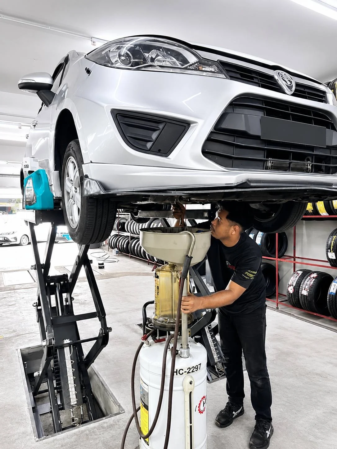 ASG technician servicing a silver car from underneath a workshop lift