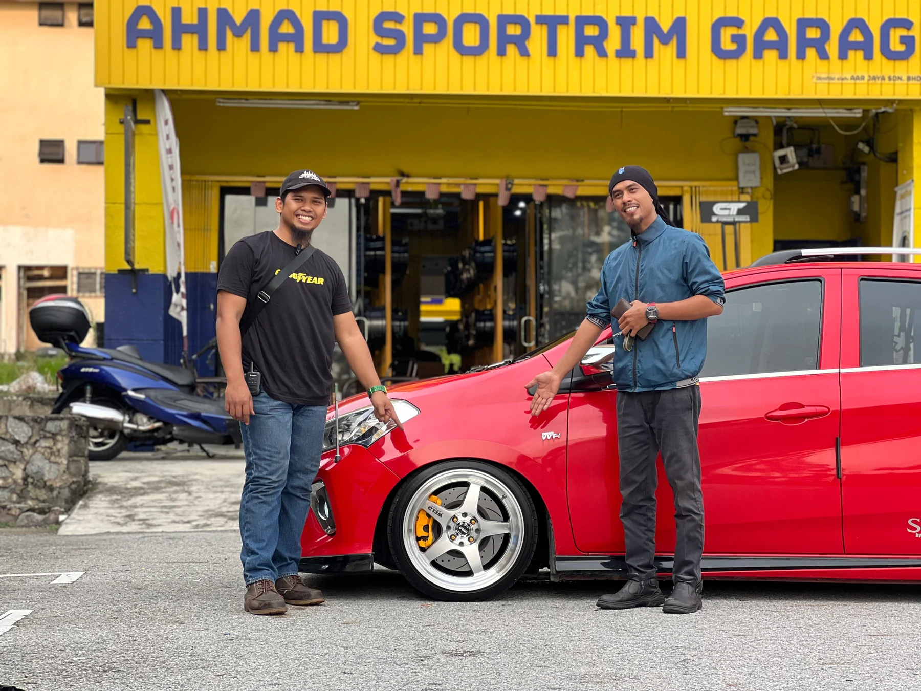ASG team member and customer with a red car outside Ahmad Sportrim Garage