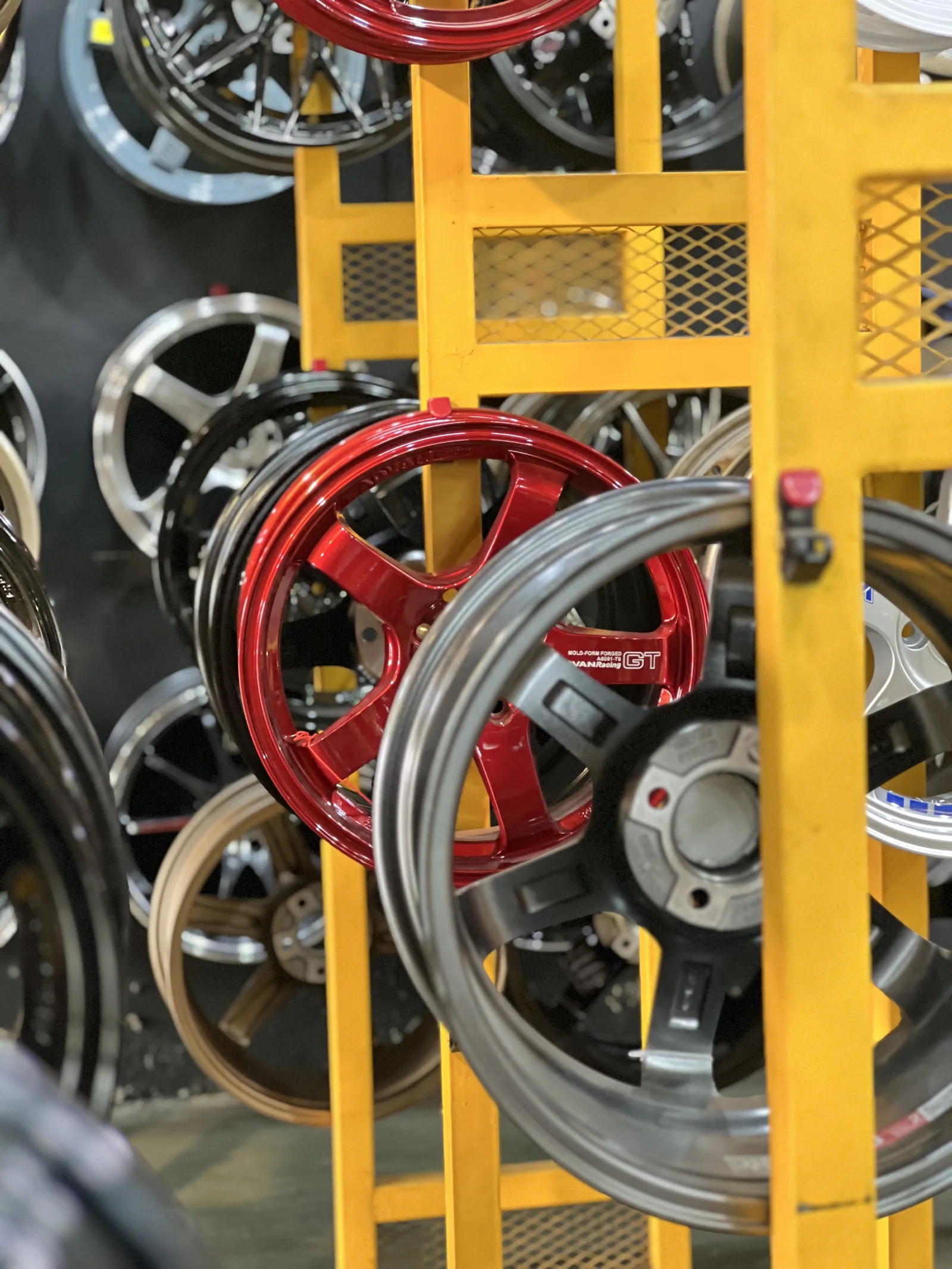 Red performance rim displayed among wheels in the ASG showroom
