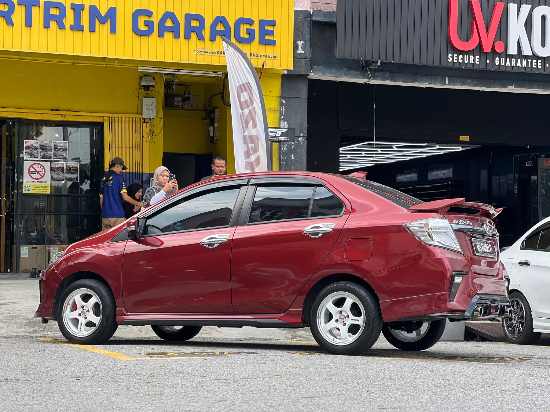 Red Perodua Bezza side profile with white five-spoke wheels