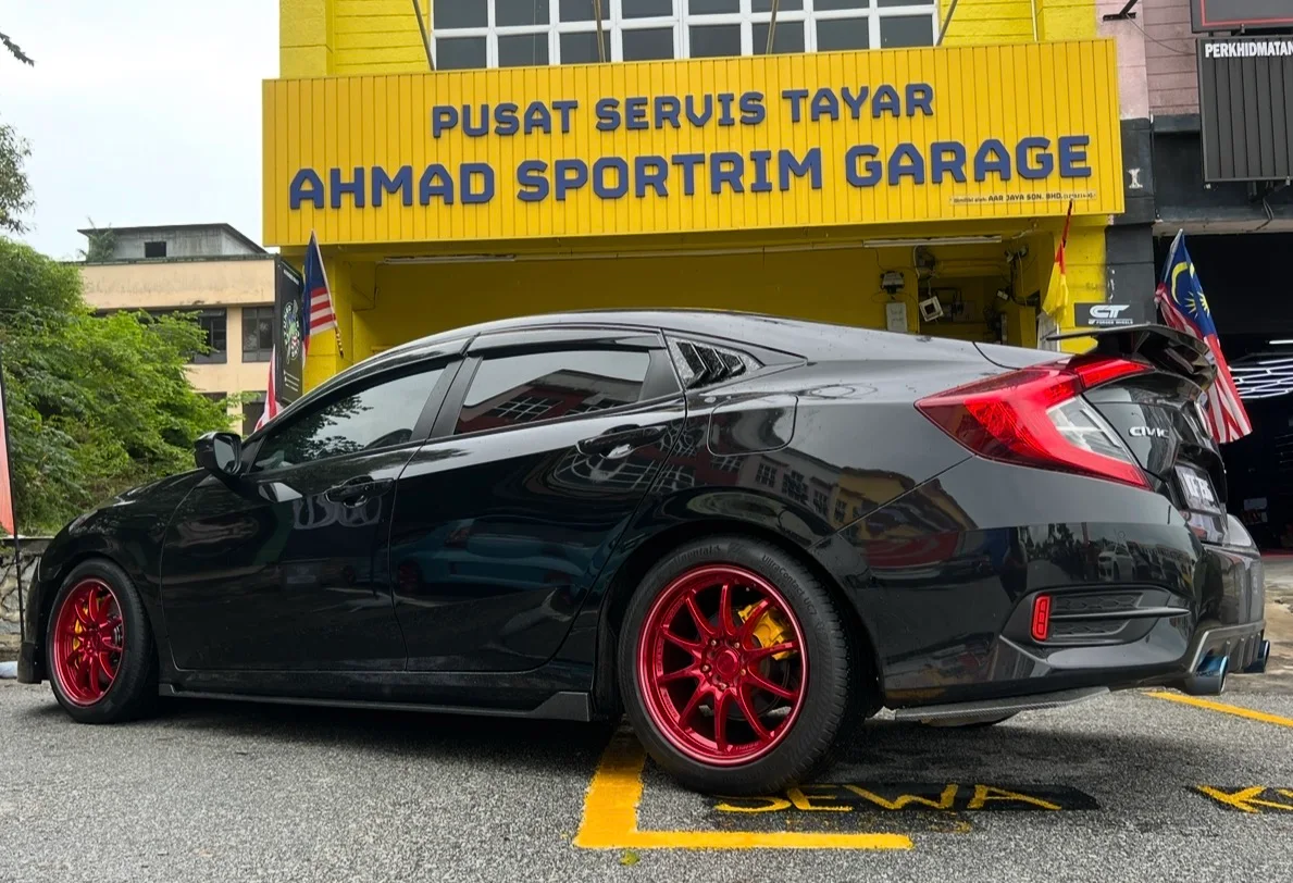 Black Honda Civic hatchback with red performance wheels outside ASG
