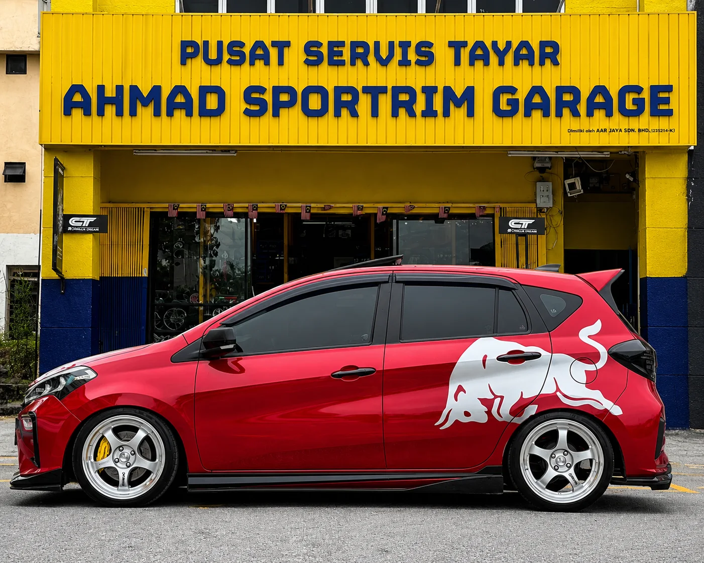 Red Perodua Myvi with white five-spoke wheels and side graphic
