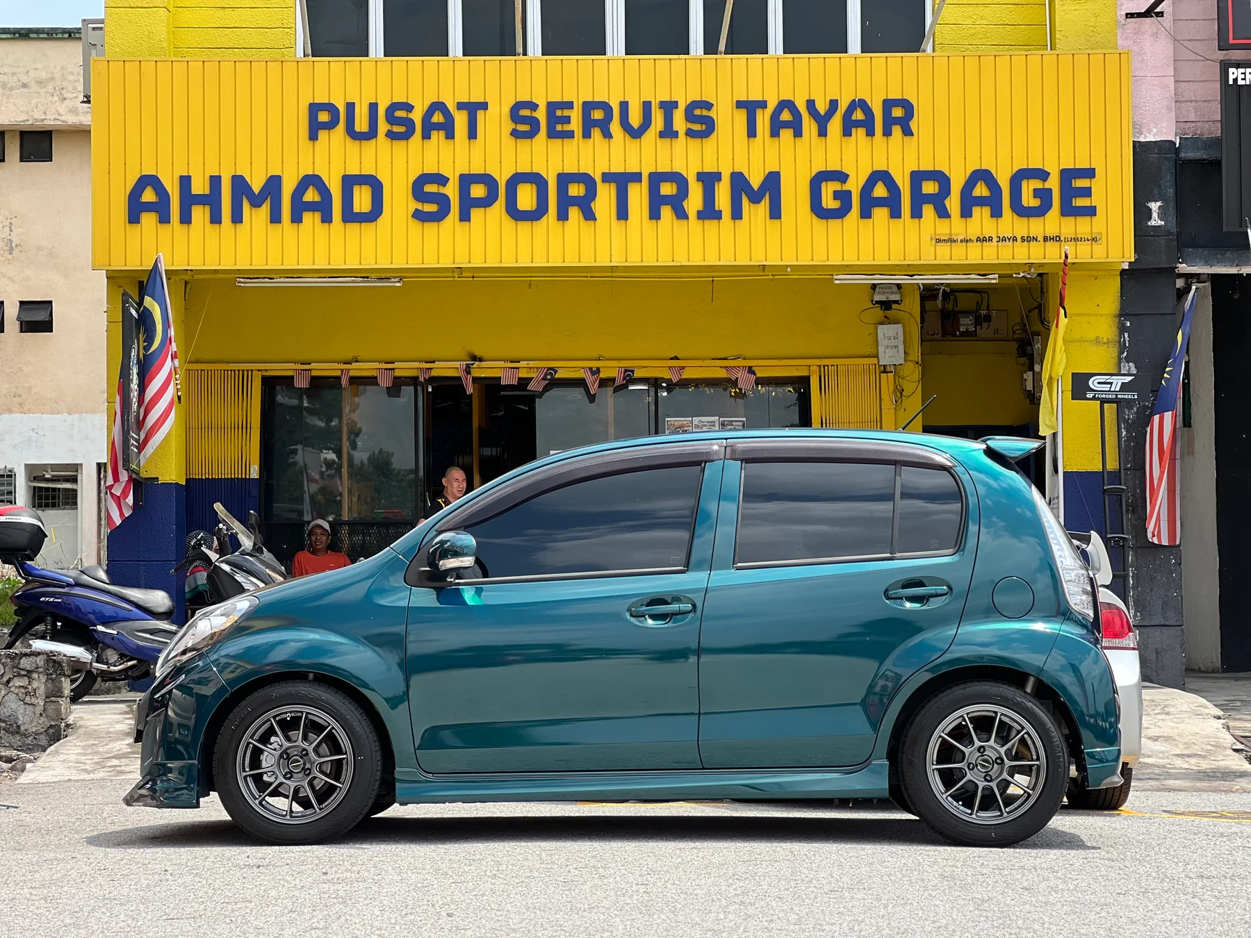 Blue Perodua Myvi with dark sport wheels outside ASG