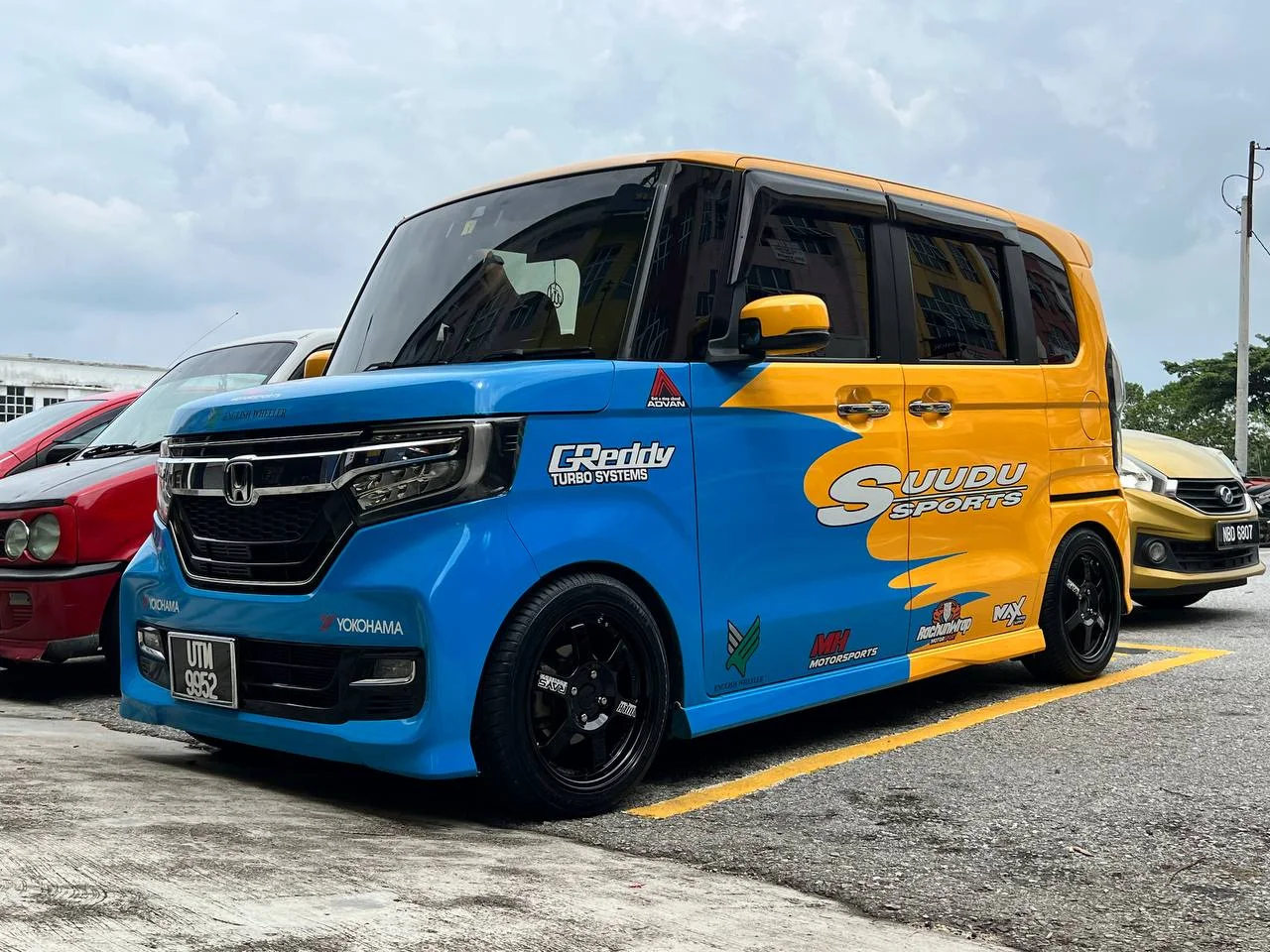 Blue and yellow Honda N-Box with black performance wheels