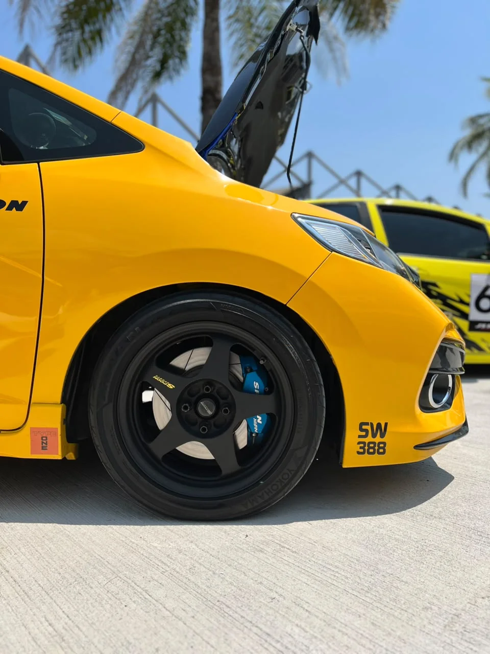 Yellow Honda with a black sport rim at an outdoor automotive event