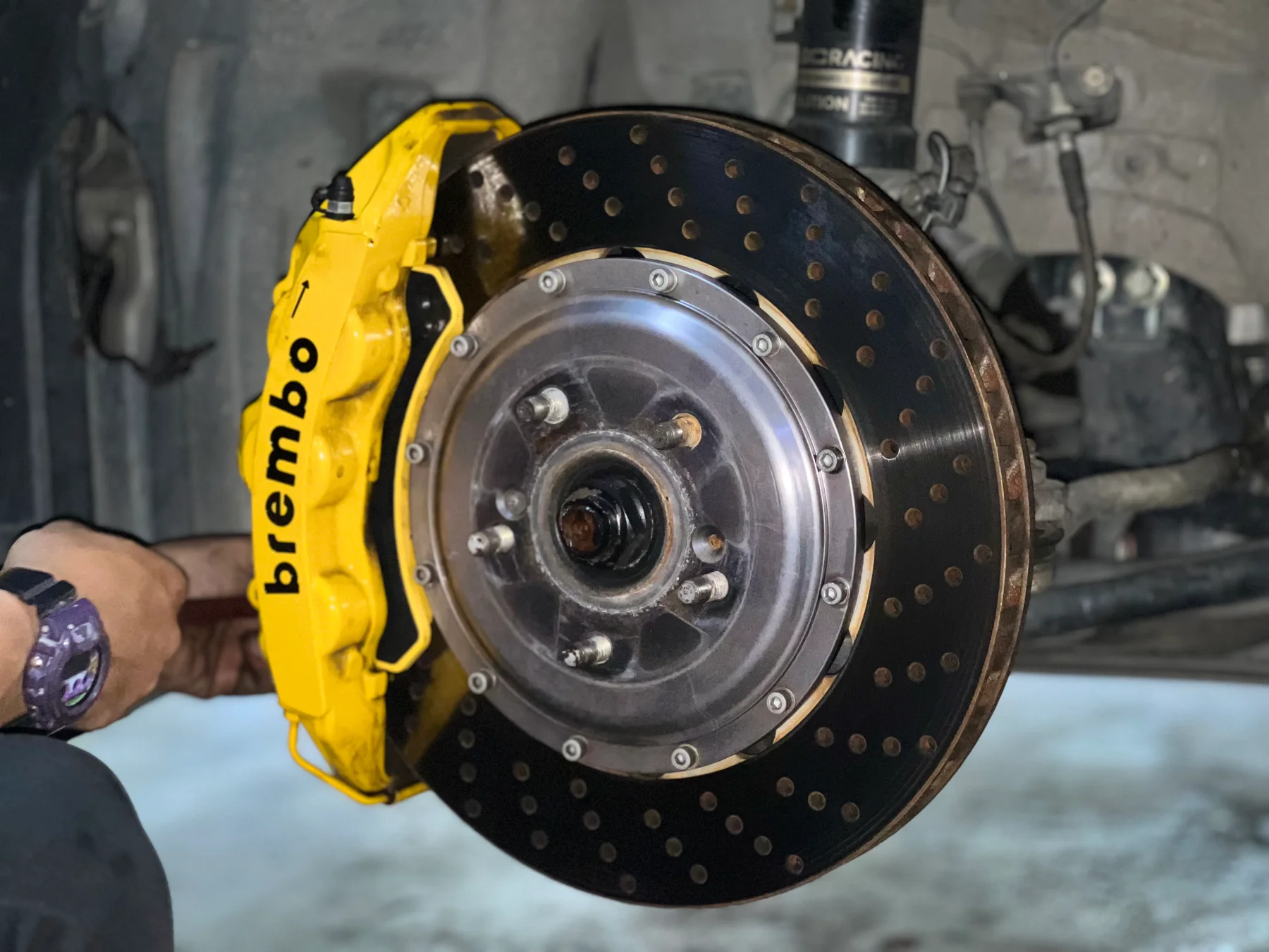 Yellow Brembo brake caliper and drilled brake disc installed on a car