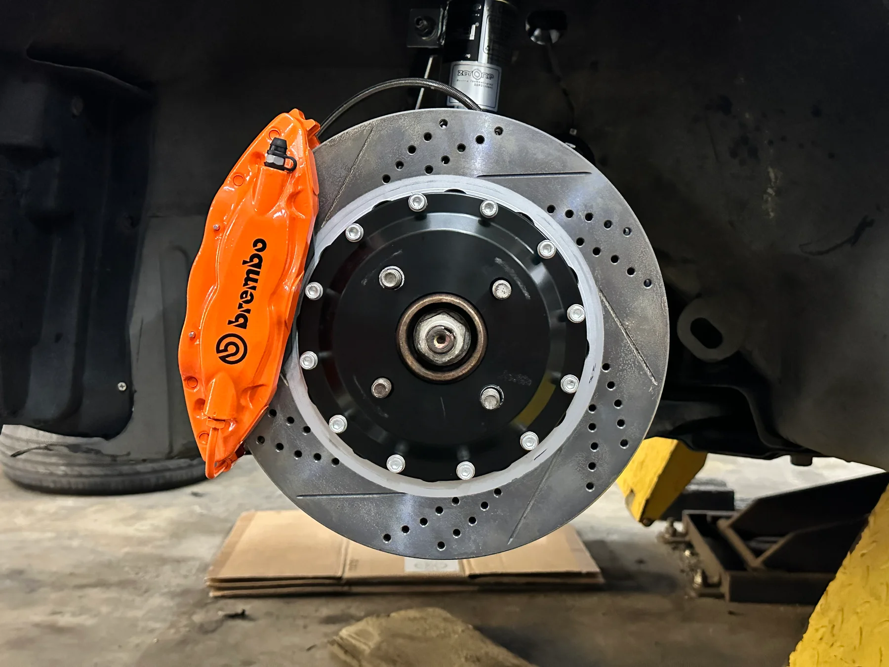Orange Brembo brake caliper and drilled brake disc installed on a car