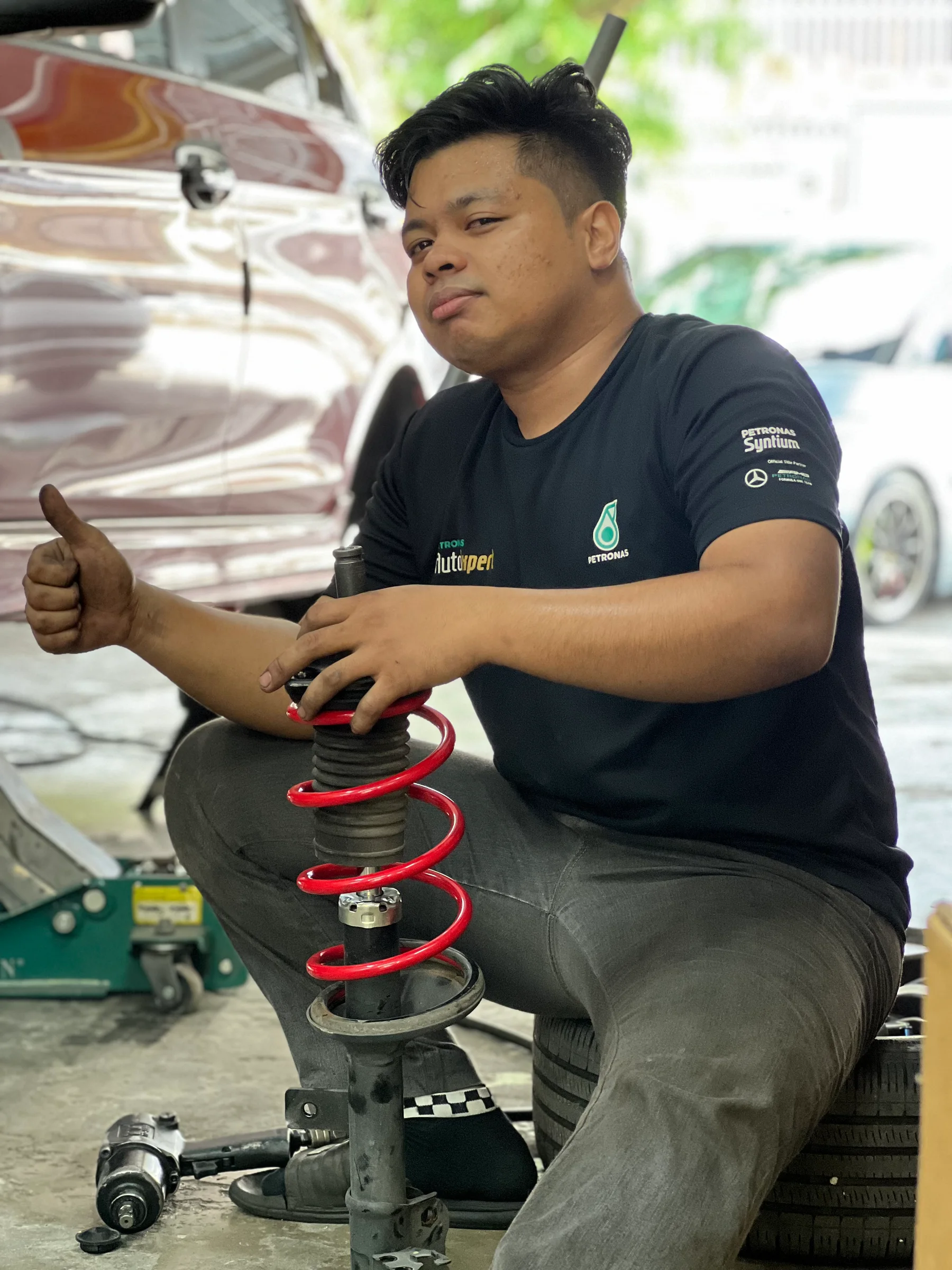 ASG technician holding a suspension strut fitted with a red coil spring