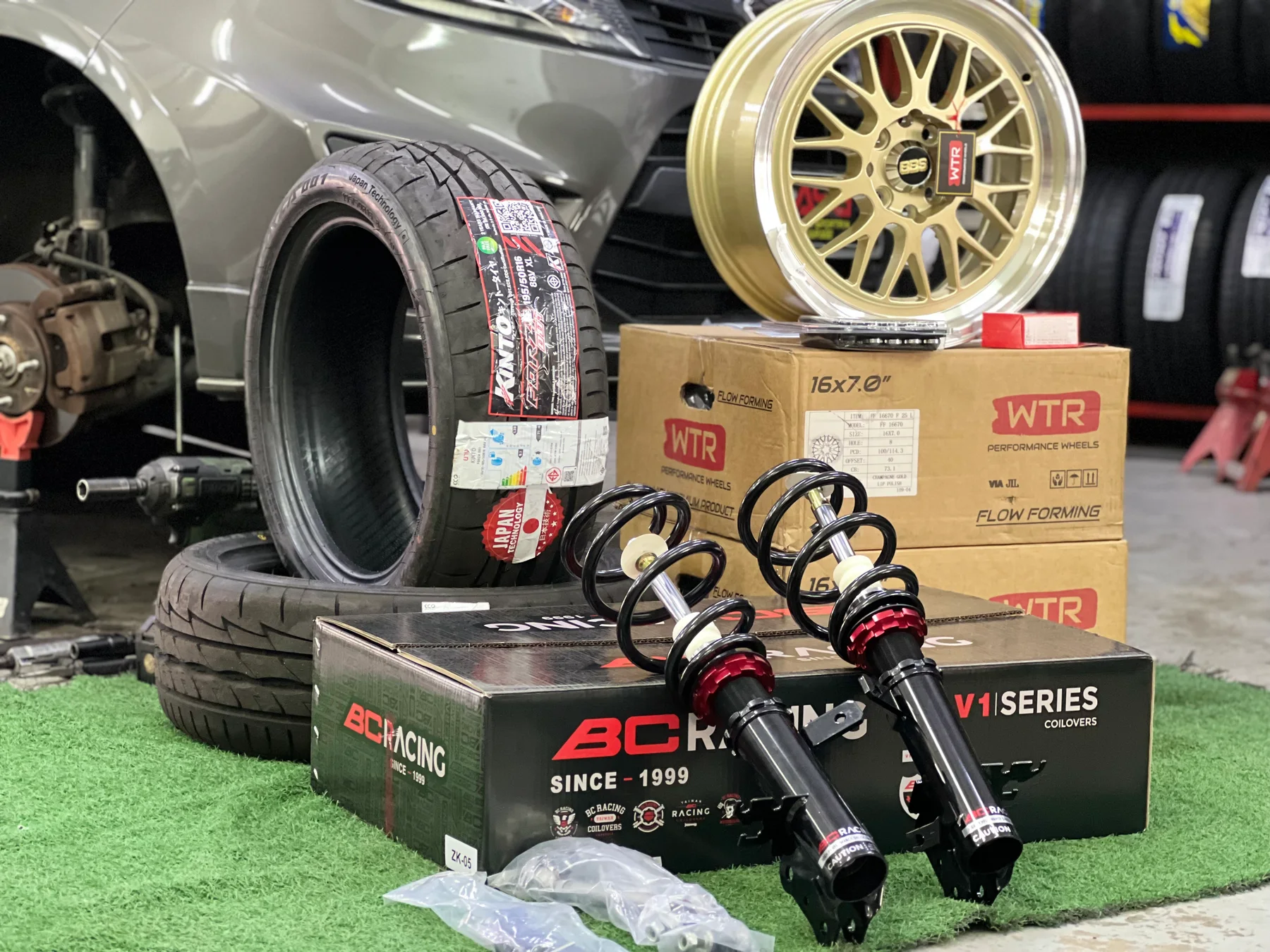 BC Racing coilovers displayed with a wheel and tyre inside the ASG workshop