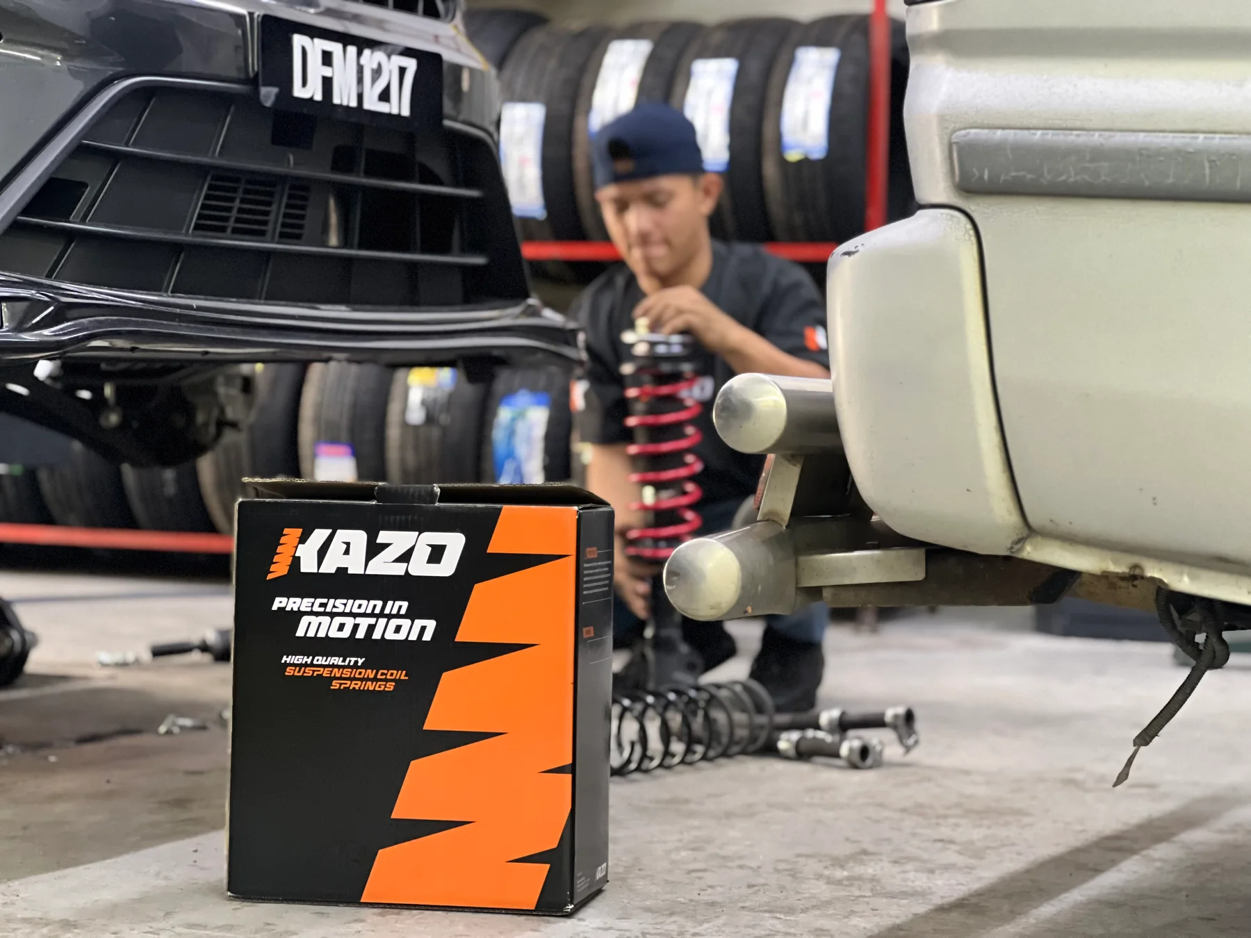 ASG technician preparing a red suspension spring beside a customer car